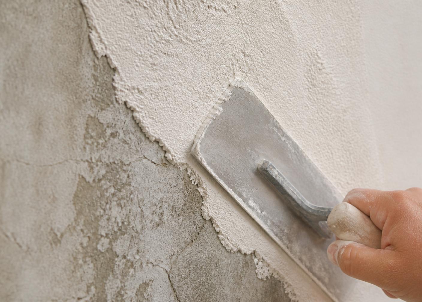 Trowel applying a matte mineral cementitious renewal finish over aged, weathered stucco